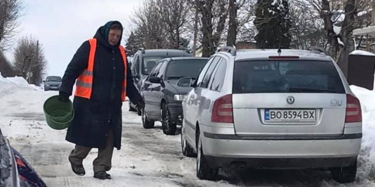 Зекономили: у місті на Тернопільщині замість техніки на дорогу випустили жіночку з відром піску (Фото)